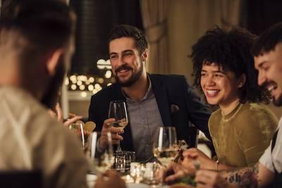 man and woman holding wine glasses smiling at a dinner party