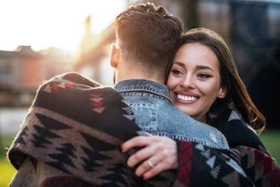 woman smiling as she hugs her male partner