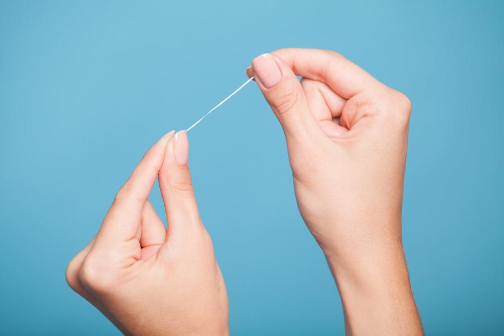 woman's hands holding dental floss