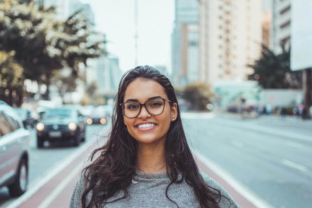 woman smiling while standing on city street