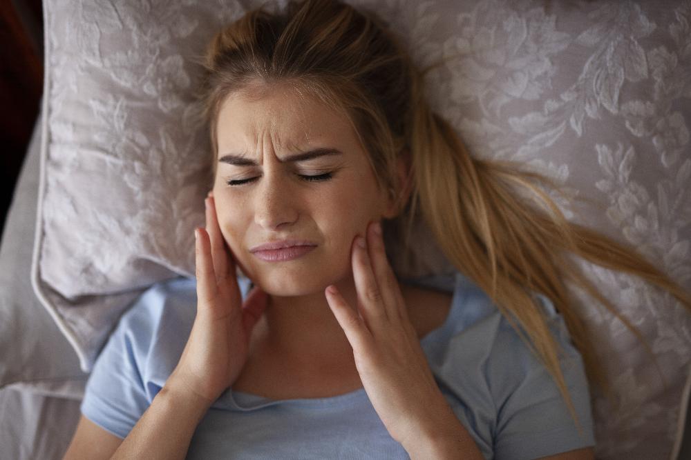woman in pain laying in bed | gum disease treatment mesquite tx