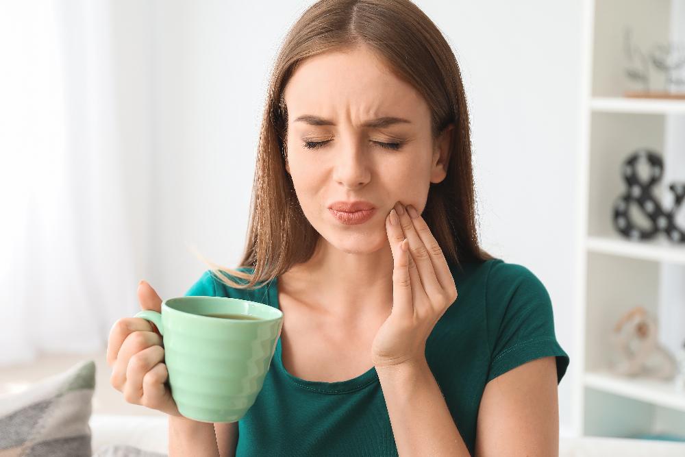 woman in pain drinking coffee | emergency dentist mesquite tx