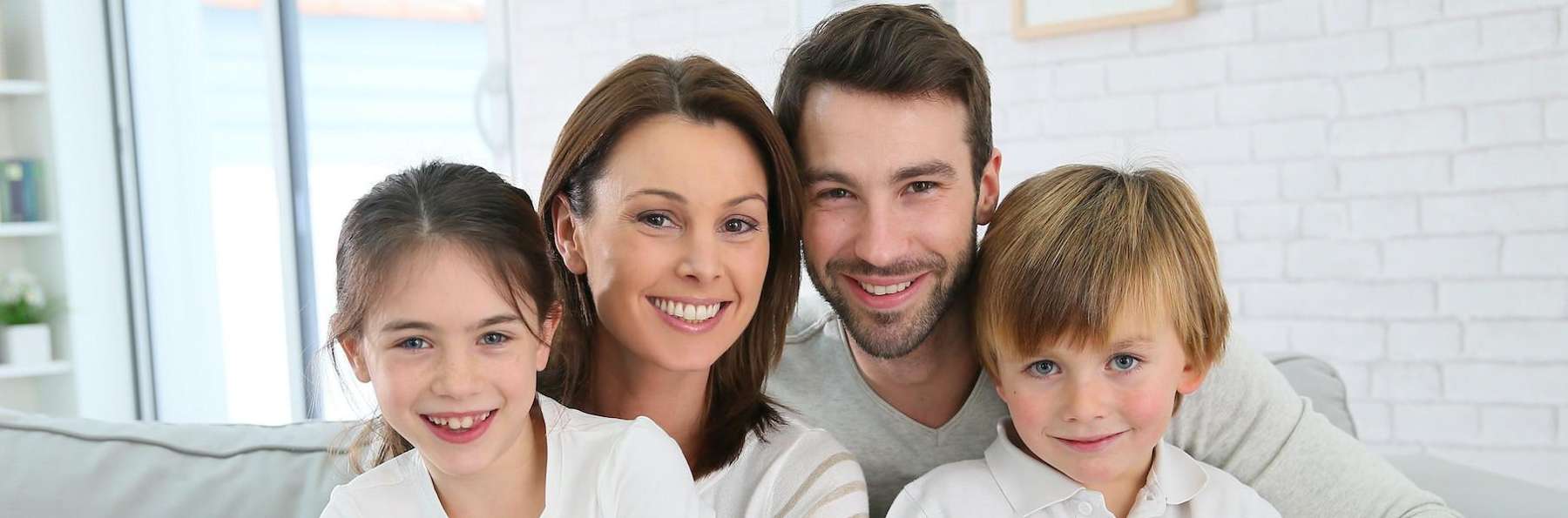 family of four hugging on couch | mesquite dental