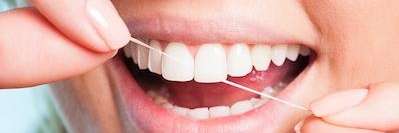 close up of person's mouth while flossing top front teeth