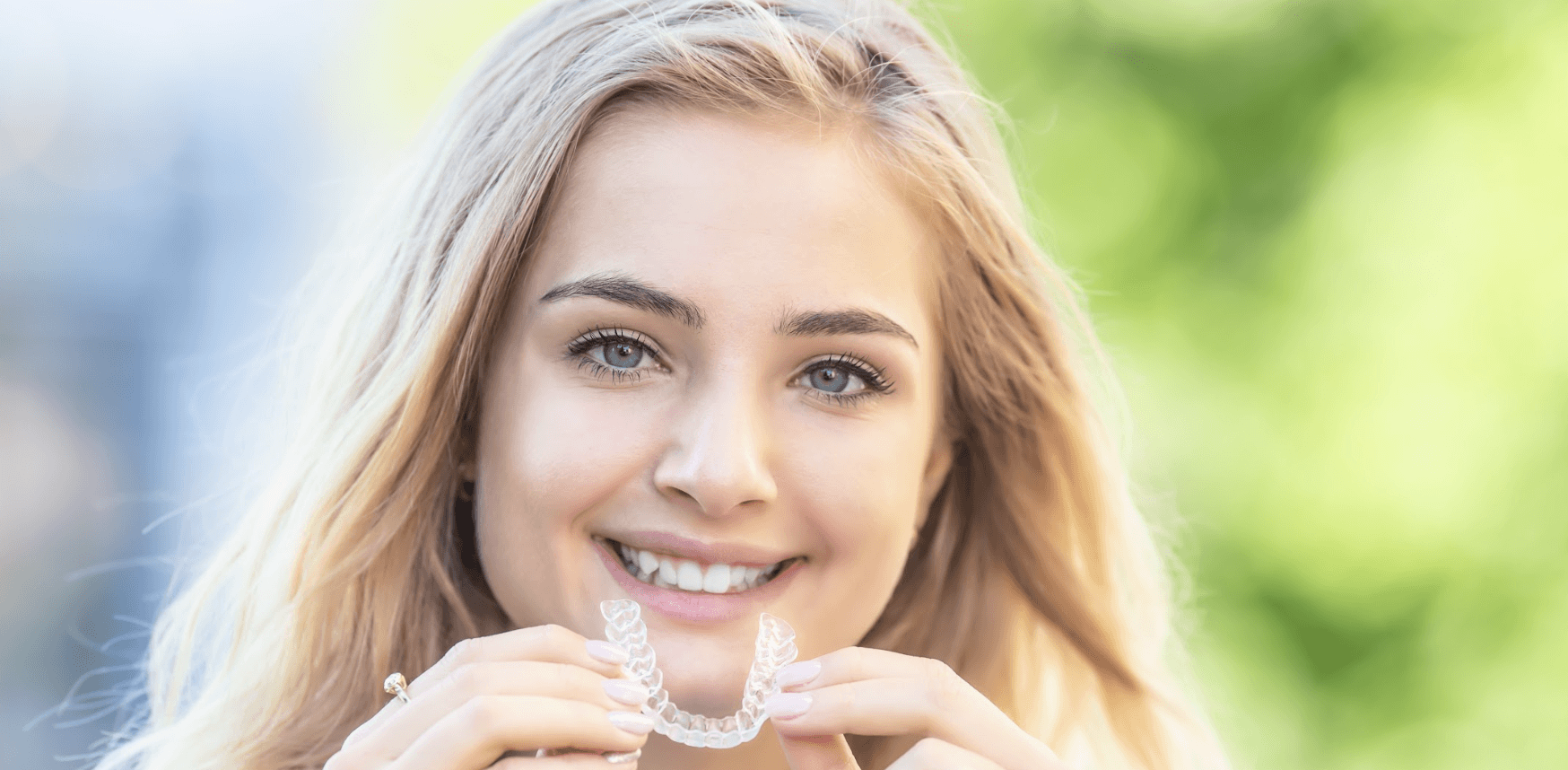 blonde woman holding invisalign | invisalign clear braces mesquite tx