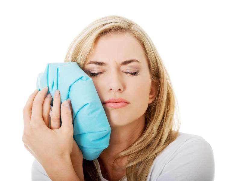 Woman holding blue handkerchief, indicating discomfort, looking for emergency dentist near the area