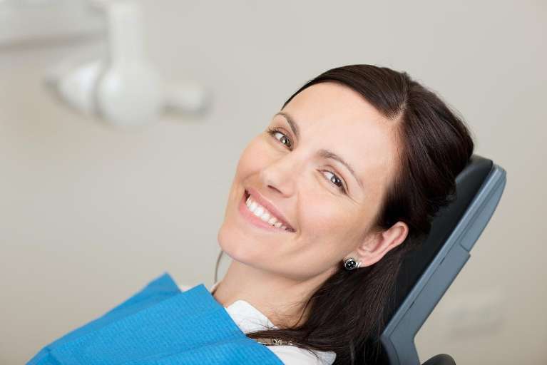 woman laying in dentist exam chair smiling | root canal mesquite tx