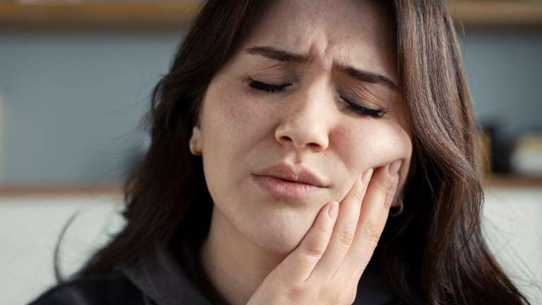 woman holding jaw from tooth pain during a dental emergency 